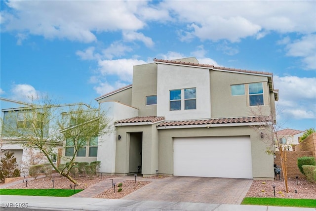 view of front of house featuring a tiled roof, decorative driveway, a garage, and stucco siding