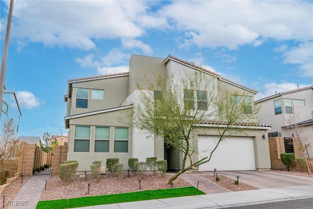 view of front of home with stucco siding, driveway, a gate, fence, and a garage