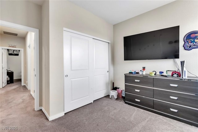 bedroom with a closet, visible vents, light colored carpet, and baseboards