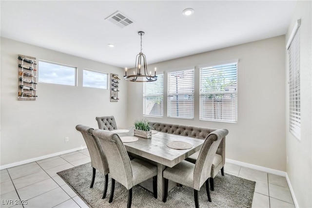 dining space with light tile patterned flooring, visible vents, a chandelier, and baseboards