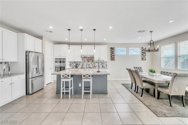 kitchen featuring visible vents, a notable chandelier, tasteful backsplash, stainless steel appliances, and light tile patterned flooring