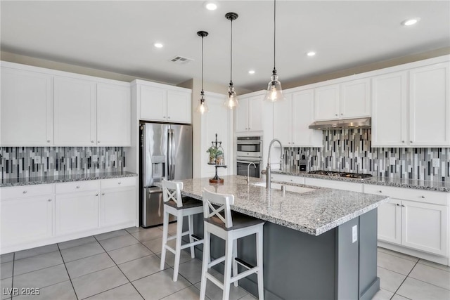 kitchen featuring visible vents, under cabinet range hood, a sink, appliances with stainless steel finishes, and light tile patterned floors