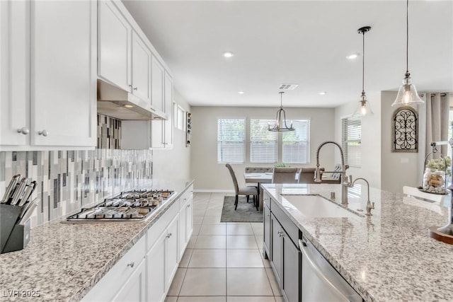 kitchen featuring light tile patterned floors, stainless steel appliances, a sink, under cabinet range hood, and backsplash