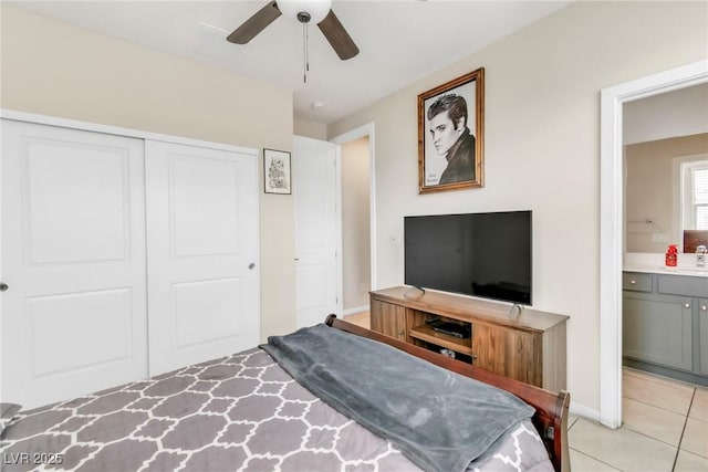 bedroom with light tile patterned floors, ensuite bath, ceiling fan, a sink, and a closet