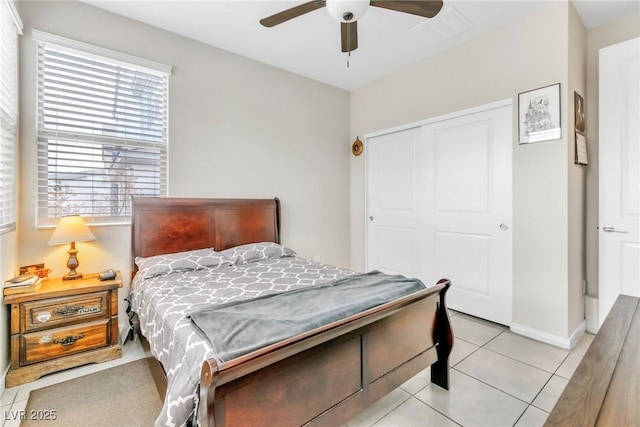 bedroom featuring light tile patterned floors, baseboards, a closet, and ceiling fan