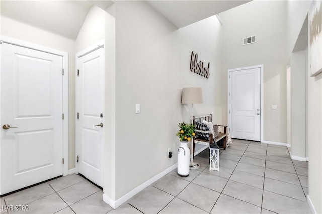 hallway featuring light tile patterned floors, visible vents, and baseboards