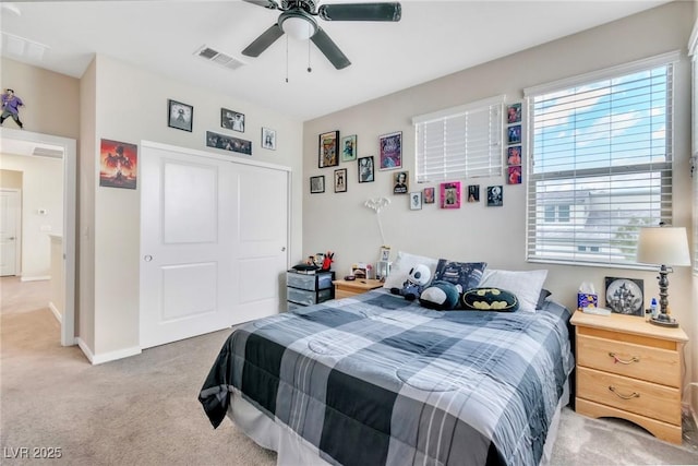 bedroom with visible vents, baseboards, light colored carpet, a closet, and a ceiling fan