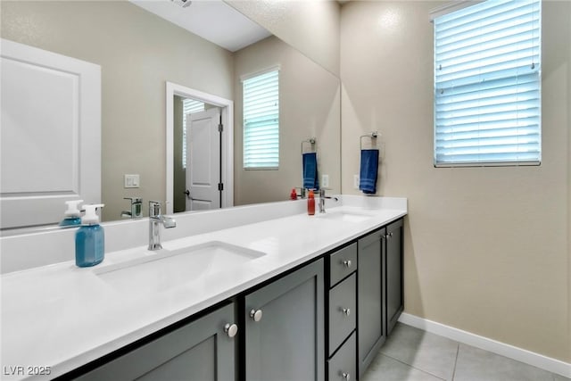 bathroom featuring a sink, baseboards, double vanity, and tile patterned flooring