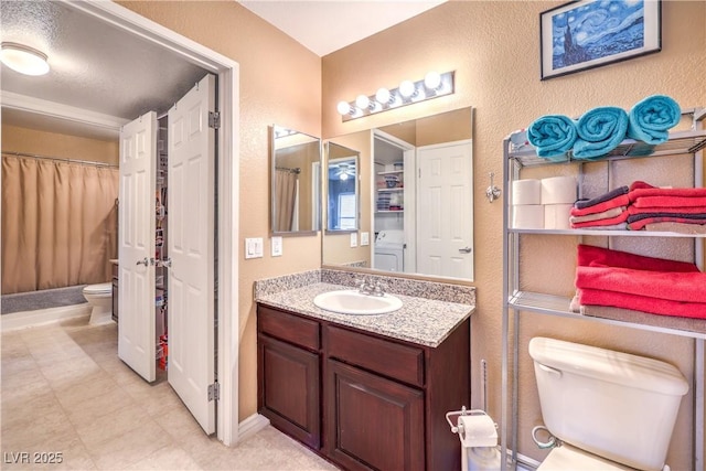 full bathroom featuring toilet, vanity, a shower with curtain, a textured wall, and washer / clothes dryer