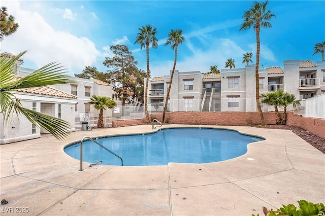 community pool with a residential view, a patio, and fence