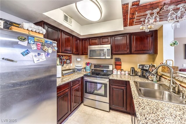 kitchen with a sink, stainless steel appliances, visible vents, and dark brown cabinets