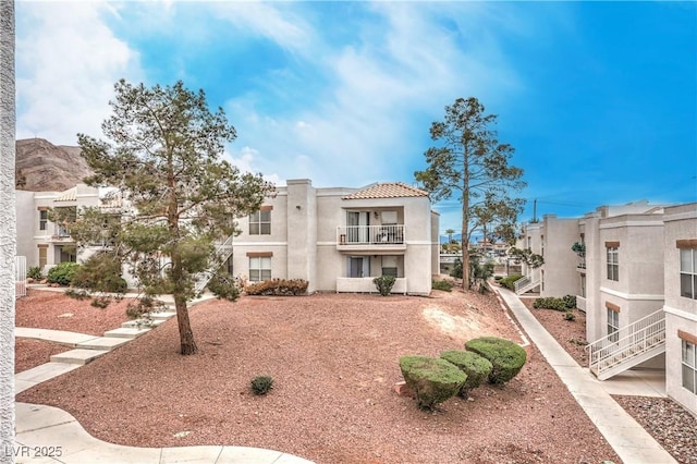 exterior space featuring a tile roof, a balcony, and stucco siding