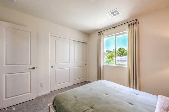 bedroom with a closet, visible vents, and carpet flooring