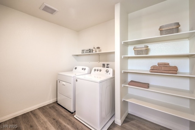 washroom with visible vents, separate washer and dryer, dark wood-style flooring, and laundry area