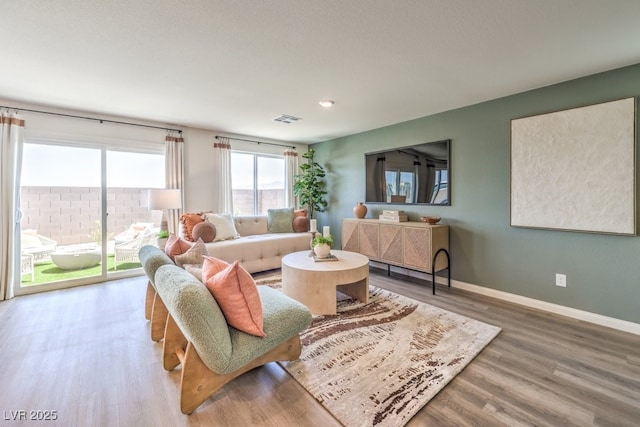 living room with visible vents, baseboards, and wood finished floors