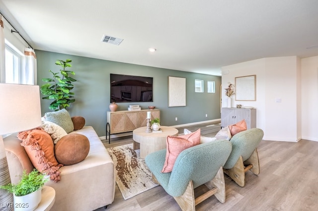 living room featuring visible vents, baseboards, and wood finished floors