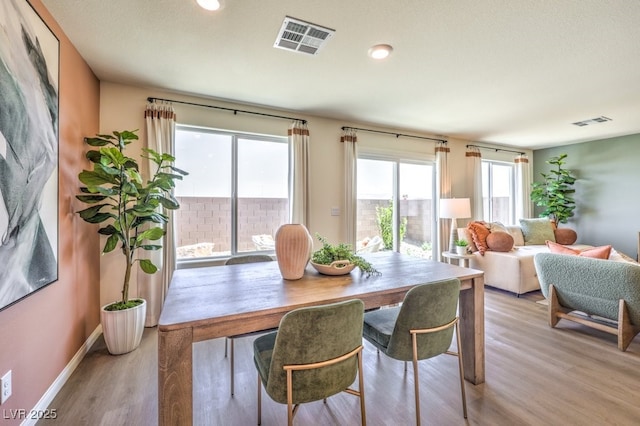 dining room featuring visible vents, baseboards, and wood finished floors