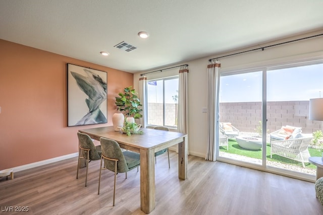 dining area with visible vents, light wood-type flooring, and baseboards