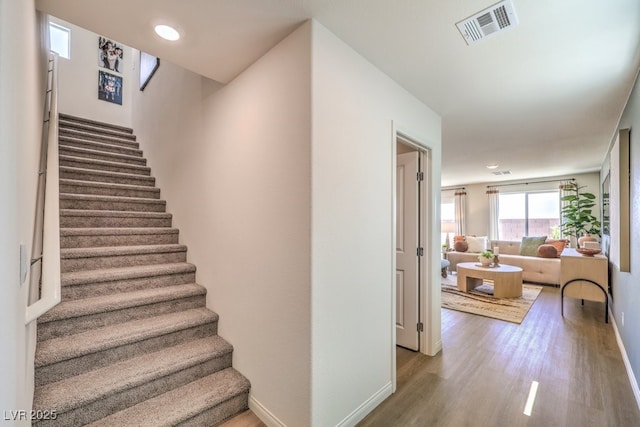 staircase featuring wood finished floors, visible vents, and baseboards