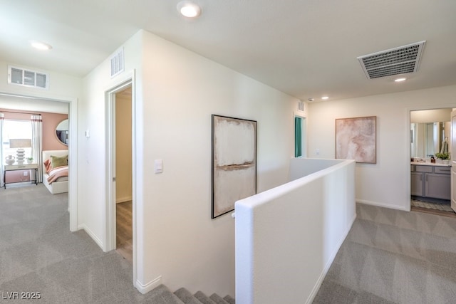 hallway with light carpet, visible vents, and recessed lighting