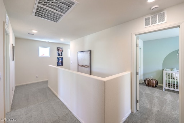 hall with carpet, visible vents, and baseboards