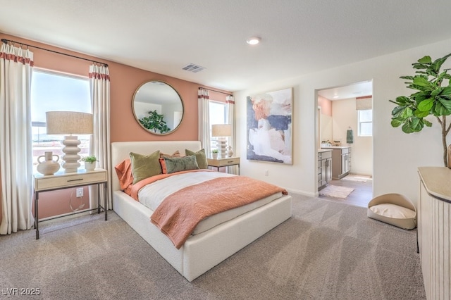 bedroom featuring ensuite bath, multiple windows, carpet flooring, and visible vents