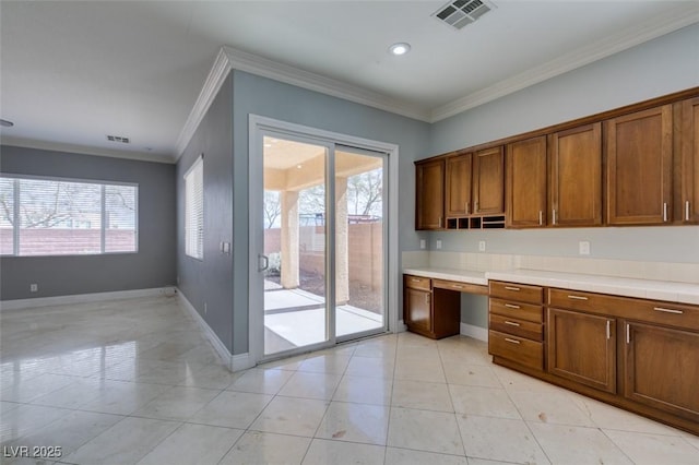 kitchen featuring visible vents, brown cabinets, baseboards, and crown molding