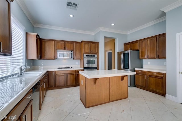 kitchen featuring a breakfast bar, a sink, a center island, appliances with stainless steel finishes, and light countertops