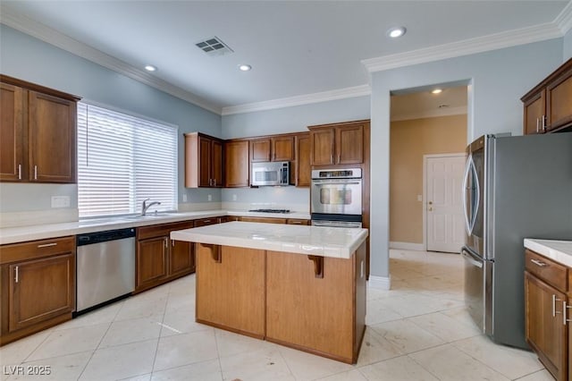 kitchen with visible vents, a kitchen island, a breakfast bar, stainless steel appliances, and light countertops