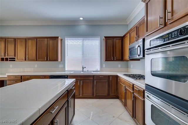 kitchen featuring a sink, stainless steel appliances, crown molding, light tile patterned floors, and tile counters