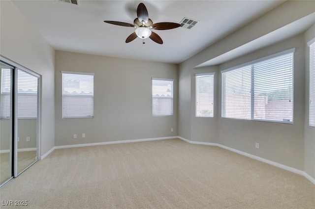 unfurnished room with ceiling fan, baseboards, visible vents, and light carpet