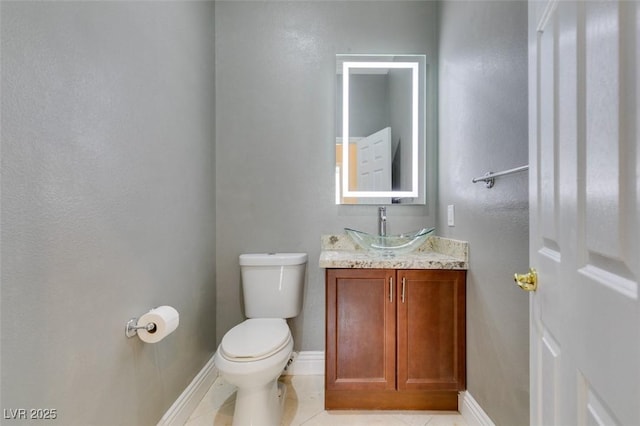 half bath featuring tile patterned floors, baseboards, toilet, and vanity