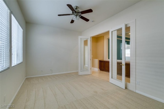 carpeted empty room with french doors, baseboards, and a ceiling fan