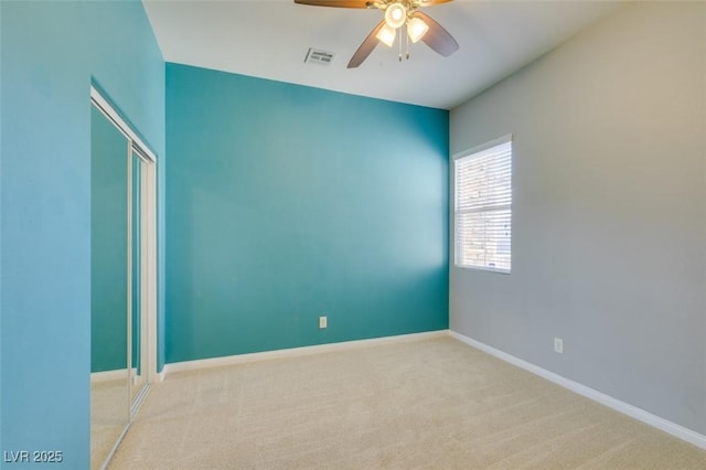 empty room with carpet flooring, baseboards, visible vents, and ceiling fan