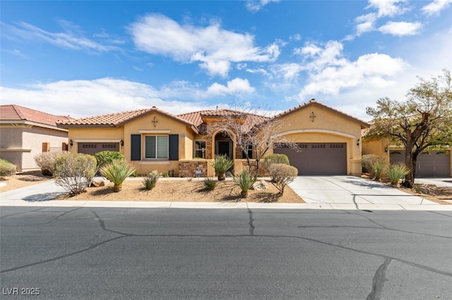 mediterranean / spanish home featuring an attached garage, driveway, and stucco siding