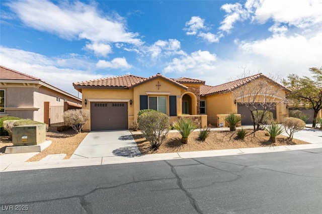 mediterranean / spanish home with a tile roof, stucco siding, concrete driveway, and a garage