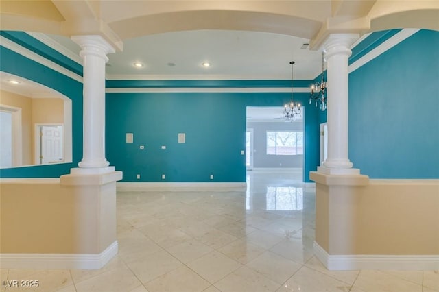 spare room featuring a notable chandelier, baseboards, ornate columns, and ornamental molding