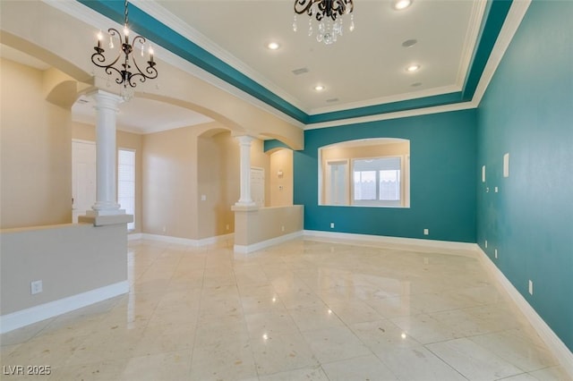 unfurnished room featuring arched walkways, an inviting chandelier, crown molding, baseboards, and ornate columns