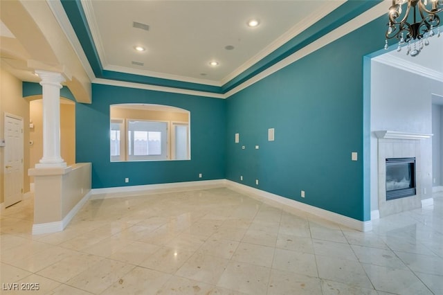 empty room featuring visible vents, a fireplace, crown molding, baseboards, and ornate columns