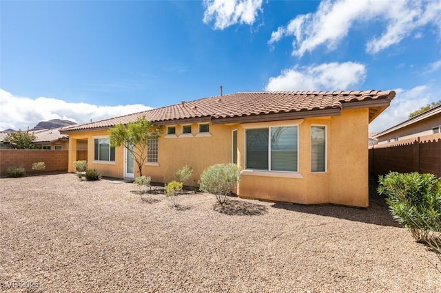 back of house with a tiled roof, fence, and stucco siding