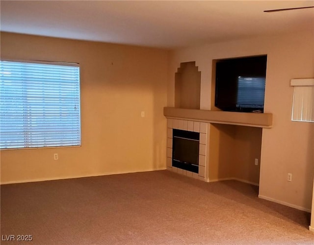 unfurnished living room with carpet flooring and a tile fireplace