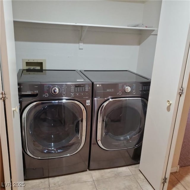 laundry area with washer and clothes dryer, light tile patterned floors, and laundry area