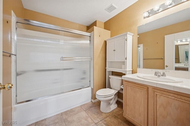 full bath with visible vents, bath / shower combo with glass door, toilet, vanity, and tile patterned flooring