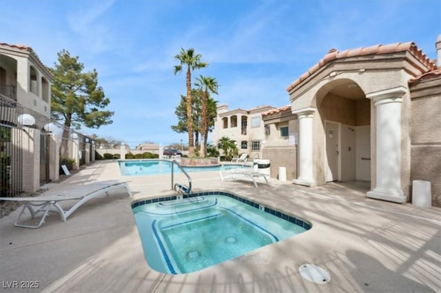 community pool featuring a patio, a residential view, and a hot tub