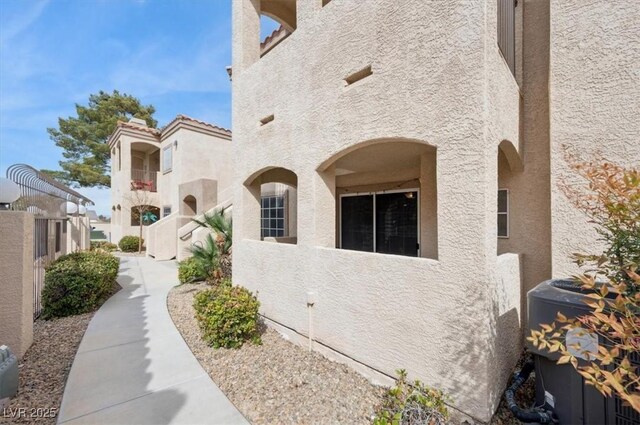 view of side of home featuring central AC unit and stucco siding