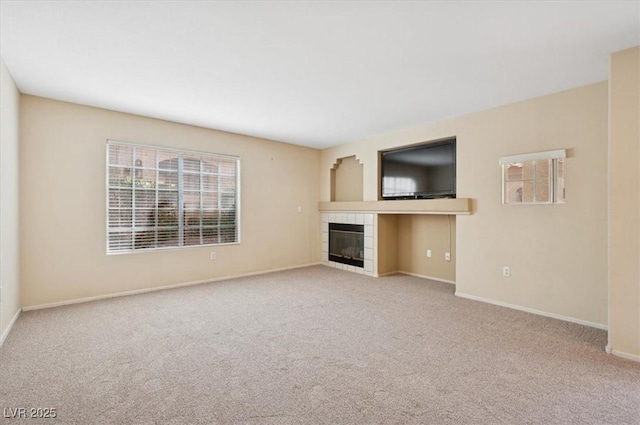 unfurnished living room featuring baseboards, a tile fireplace, and carpet flooring
