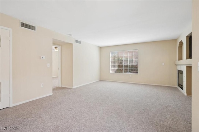 unfurnished living room featuring a fireplace, carpet, visible vents, and baseboards