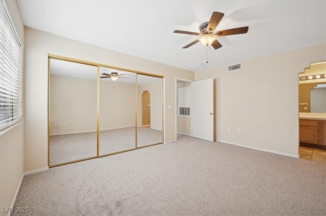 unfurnished bedroom with arched walkways, light colored carpet, multiple windows, and visible vents