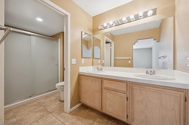 bathroom featuring tile patterned flooring, a sink, a shower stall, and double vanity