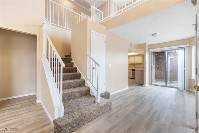 staircase with a high ceiling, baseboards, and wood finished floors